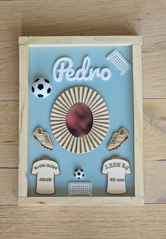 Quadretto che rappresenta elementi del gioco del calcio, come palloni, magliette e porte. Nelle magliette ci sono i dati di nascita del bambino per cui il quadretto è stato fatto.