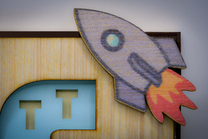 Quadretto decorativo personalizzato con elementi in rilievo dipinti a mano con colori atossici. Nome del bambino ricavato dal taglio di legno e di carta.