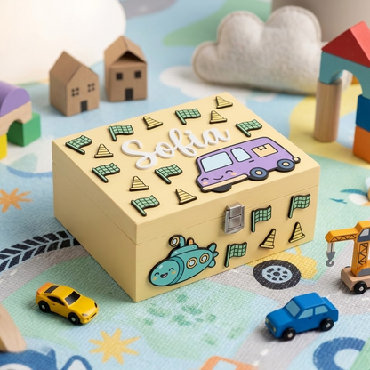 Scatola dei ricordi in legno personalizzata per bambini con nome Sofia in rilievo. Decorata con applicazioni a forma di camper viola, sottomarino azzurro, bandierine a scacchi e coni. Scatola portagiochi ambientata su un tappeto con macchinine e costruzioni in legno.