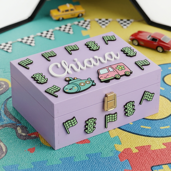 Scatola dei ricordi in legno lilla personalizzata con il nome Chiara in rilievo bianco, decorata con applicazioni 3D a tema trasporti tra cui un furgoncino rosa, un sottomarino, semafori e bandiere a scacchi, dotata di chiusura in metallo dorato.