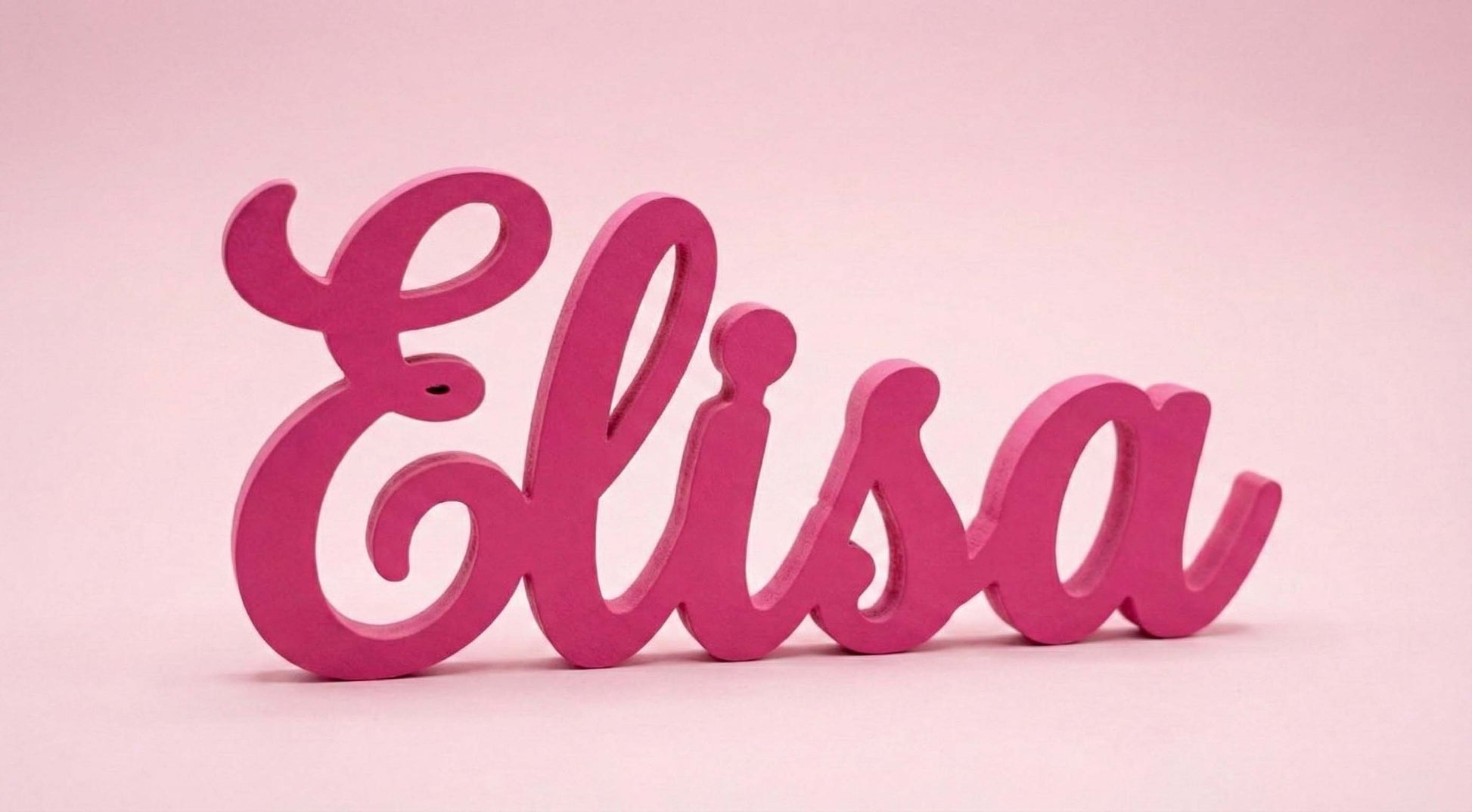 Scritta in legno rosa personalizzata con il nome Elisa, autoportante, fotografata su sfondo rosa pastello.