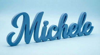 Scritta in legno azzurra personalizzata con il nome Michele, fotografata su sfondo azzurro soft.