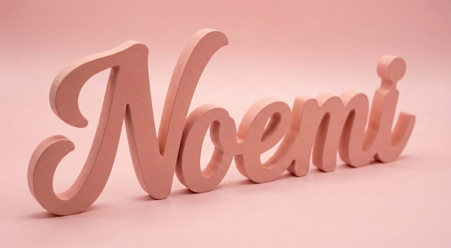 Scritta in legno rosa cipria personalizzata con il nome Noemi, fotografata su sfondo rosa pastello.