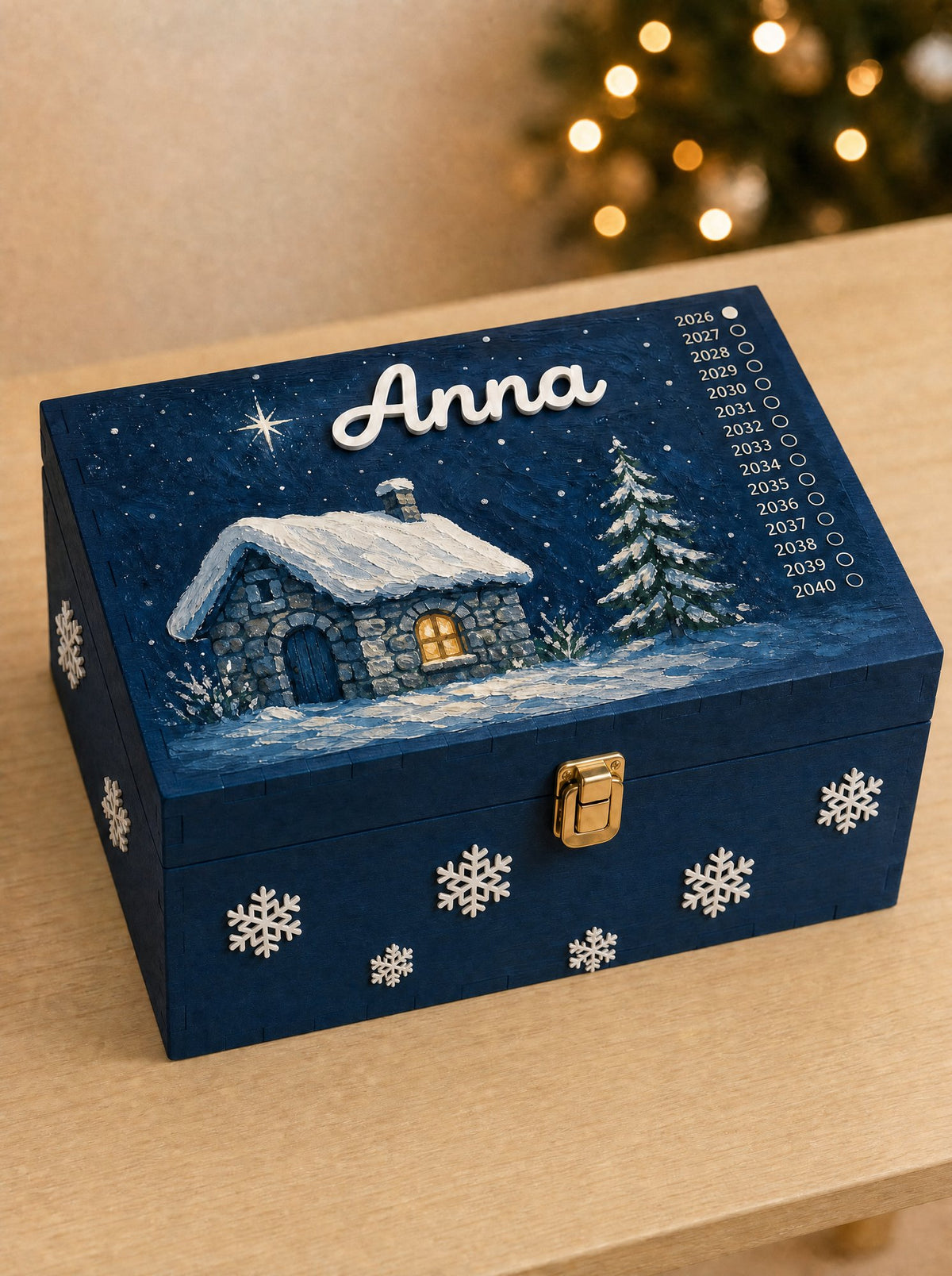 Scatola Blu Notte con la scena La casa nel bosco, nome Anna in corsivo, su un tavolo con le luci dell'albero