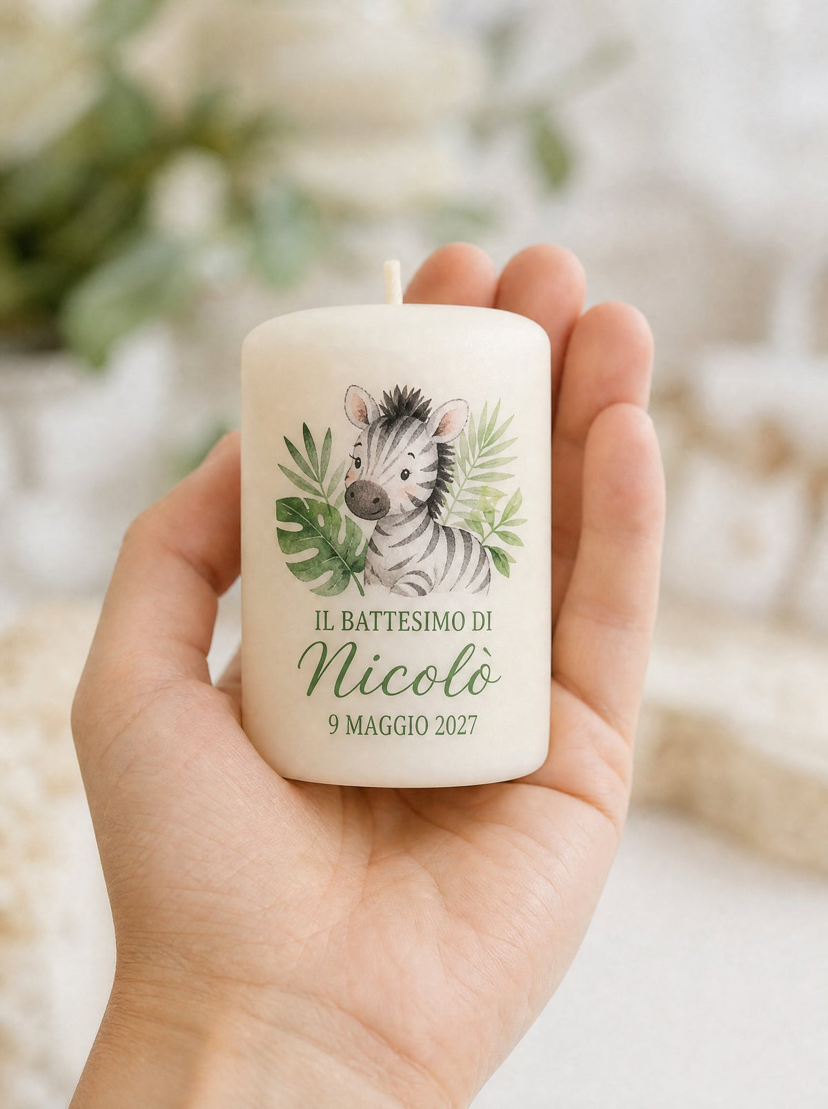 Candela battesimo con la zebra appoggiata sul palmo di una mano, per mostrarne la misura