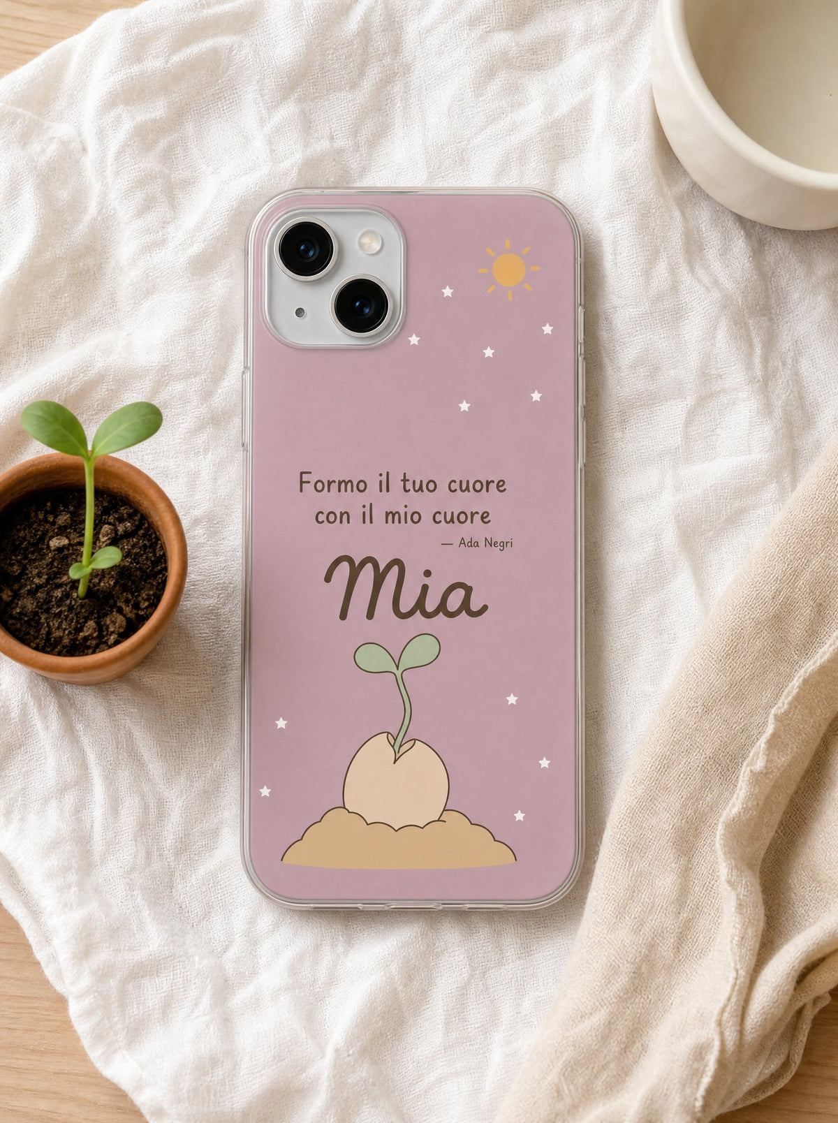 Cover per la mamma con un seme che germoglia, frase di Ada Negri e nome Mia, su un iPhone 15 visto dall'alto