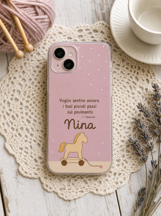 Cover per i nonni con un cavallino di legno a rotelle, frase di Stevenson e nome Nina, su un iPhone 15 visto dall'alto