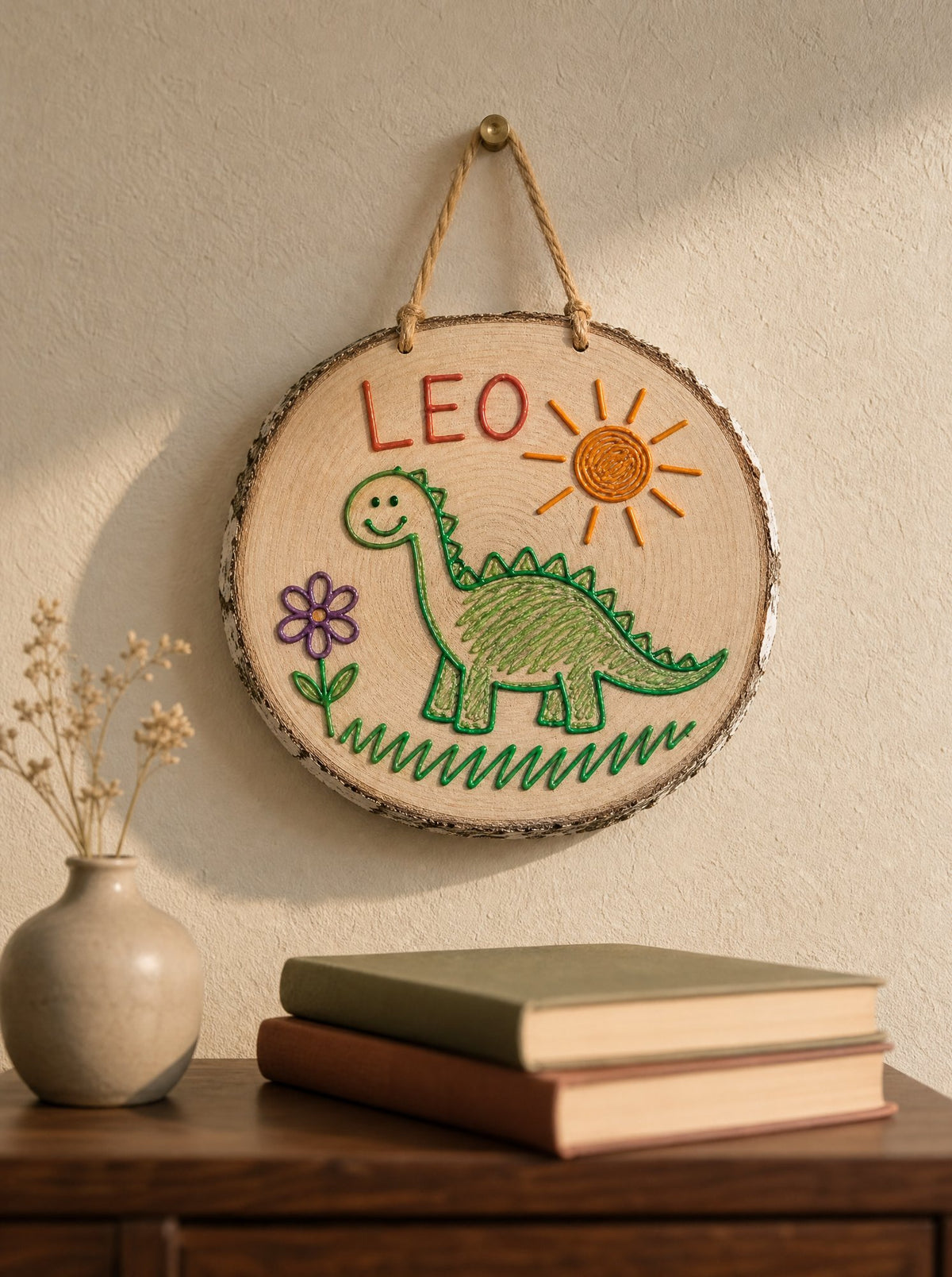 Fetta con il dinosauro di Leo appesa in casa dei nonni, parete chiara e credenza scura, nome LEO in rosso