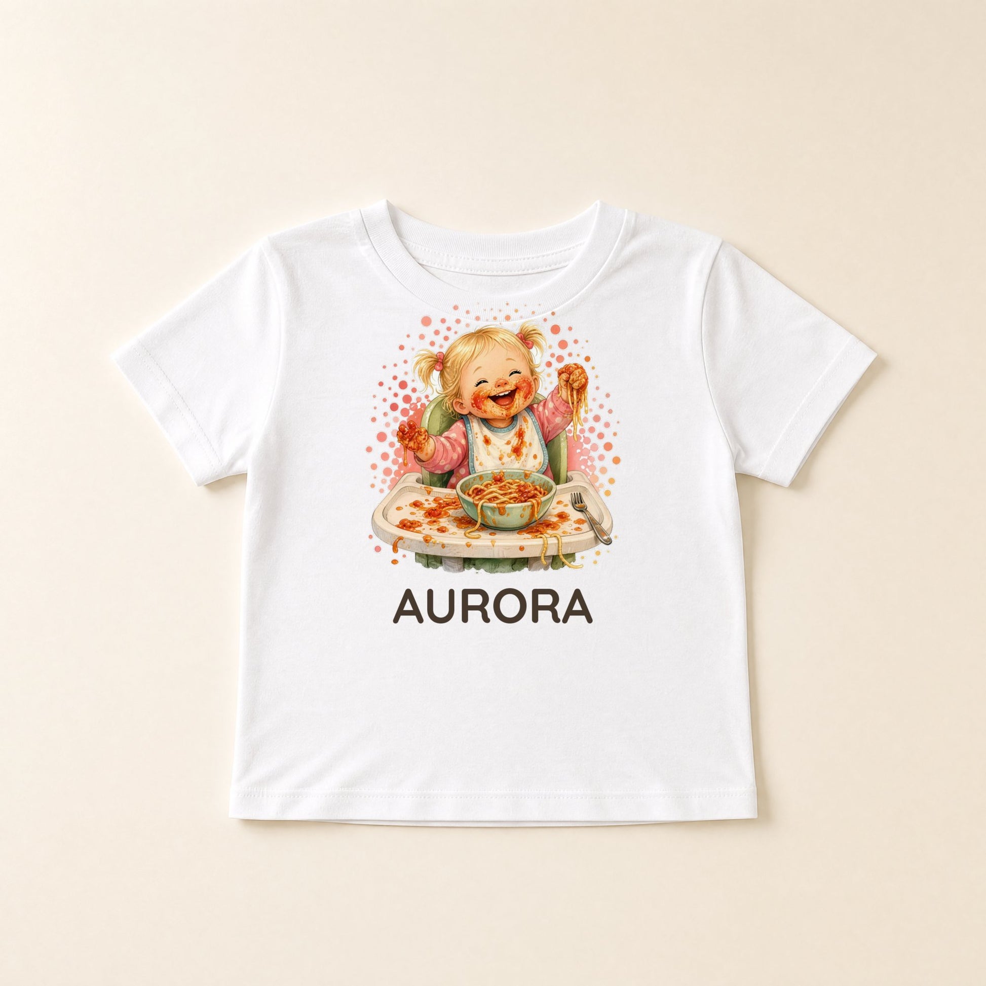 Maglietta bianca distesa con la bimba che mangia da sola e il nome Aurora