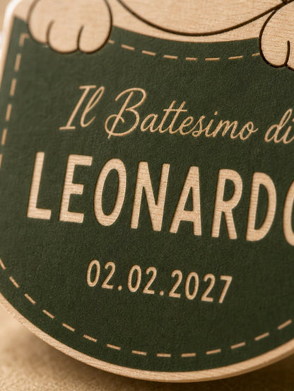 Primo piano del tag: la venatura del legno visibile dentro le lettere del nome sul campo verde ulivo.